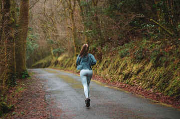 Woman running along road in forest