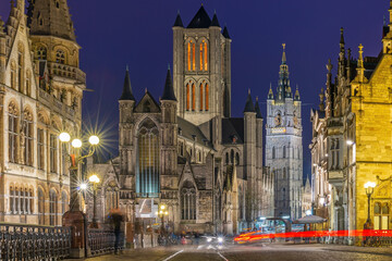 Ghent (Gent) city center at night with blurred motion of people and transportation vehicles with Saint Bavo Cathedral and belfry, East Flanders, Belgium.