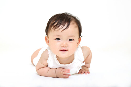 白背景でハイハイし微笑む赤ちゃんの正面。元気,健康,成長,育児イメージ