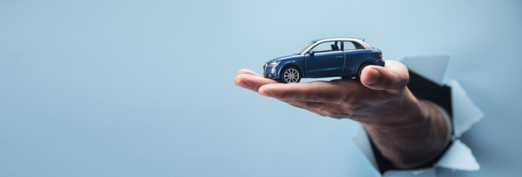 Man's hand holding a car on a blue background
