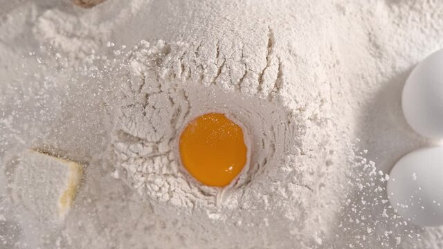 Making Homemade Dough by Adding Egg Yolk to Heap of Cake Flour in Slow Motion 1000 fps - Top View
