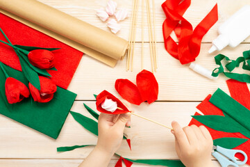 Fototapeta premium How to make a tulip flower out of paper and marshmallows at home. Marshmallow inside a red tulip bud. Hands make a red tulip. Step-by-step instruction. DIY children's art project
