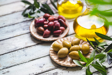 Variety of black and green olives and olive oil in bowls on white background close up
