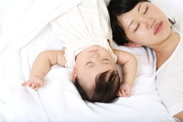 Obraz na płótnie Canvas 新生児と一緒に昼寝するお母さん。育児疲れイメージ