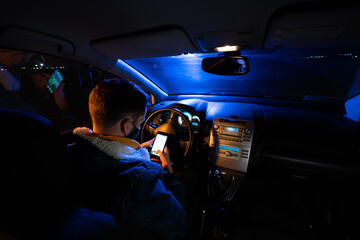 chico joven mirando el movil , sentado al volante