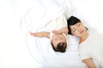 新生児と一緒に昼寝するお母さん。育児疲れイメージ