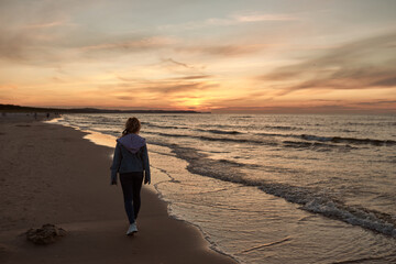 beautiful natural girl walking and admiring the sunset by the sea,