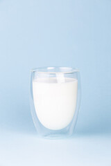 Glass with fresh tasty milk on a blue