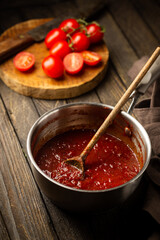 Classic homemade Italian tomato sauce with basil for pasta and pizza in the pan on wooden background.