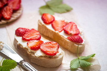Strawberries sandwiches with cream cheese and on paper, light background