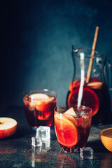 Refreshing red wine sangria or punch with fresh fruits in glasses and pincher on black background