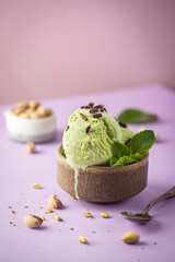 Homemade pistachio ice cream with chopped pistachios on bright pink and purple background