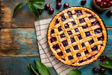 Delicious homemade classic cherry pie with a flaky crust on blue rustic background, top view
