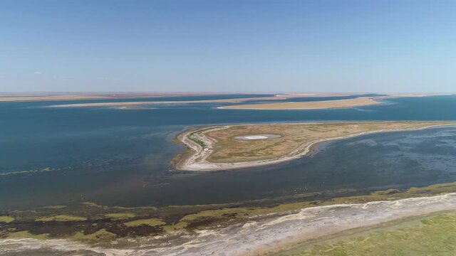 Fly over a green field towards an island in the water