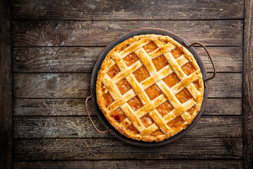 Summer apricot or peach pie homemade on wooden background, top view. Delicious fruit dessert. Fruit cake. Copy space.