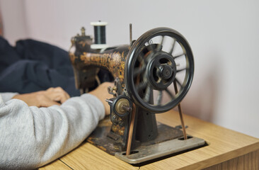 Close-up view of sewing process. Female hands stitching with a vintage sewing machine. Selective focus.