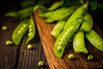 Pods of green peas on a old wooden background close up, soft focus