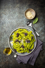 Green Tagliatelle pasta with purple cauliflower on blue background, top view