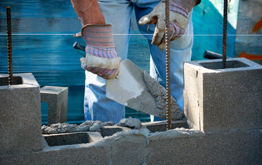 Construction site: building wall of concrete block.
Mason in laying concrete blocks
