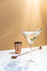Cocktail vodka martini with green olives on orange background with bright beautiful shadows