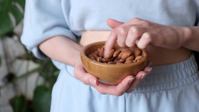 Unrecognizable caucasian woman eating almond nuts. Healthy vegan food