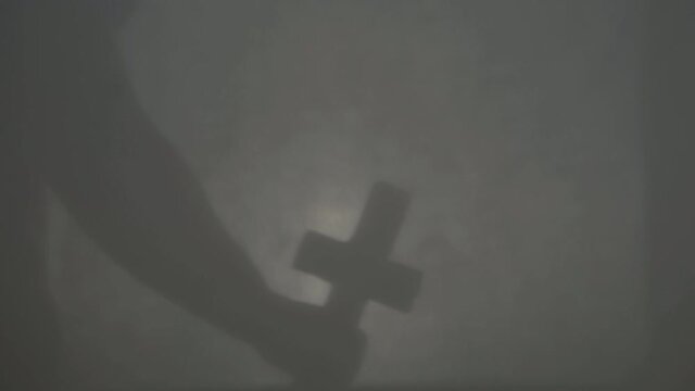 Hand holds up crucifix cross in darkness