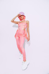 Girl 90s style posing in white studio.  Bucket hat. Trendy pink jumpsuit. Urban and fashion concept