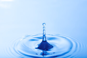 Drop of water. Water droplet falling impact with water surface. causing rings on water surface..