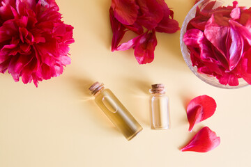 Natural cosmetics and spa concept. Bottles with essence and piones petals flat lay on a biege background
