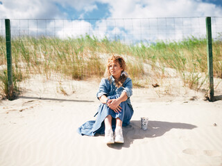 beautiful natural girl sitting on the beach with coffee, denim jacket,