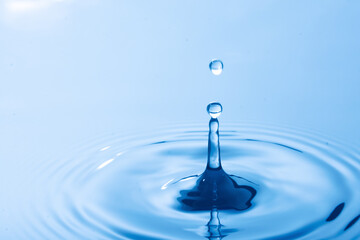 Drop of water. Water droplet falling impact with water surface. causing rings on water surface..