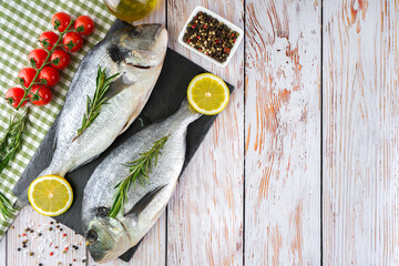 Fresh fish dorado on white wooden background with ingredients for cooking