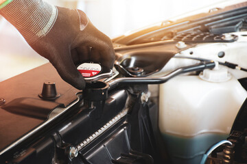 Mechanic hand is opening the radiator cap to check the coolant level of the car radiator
