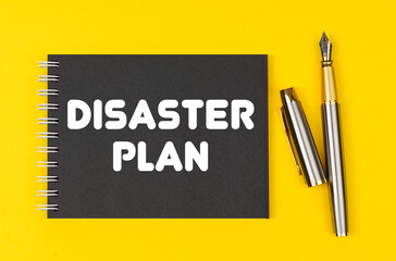 On a yellow background lies a pen and a black notebook with the inscription - Disaster Plan