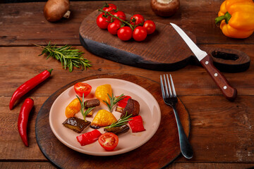 Antipasta on a plate on a wooden table next to fresh vegetables on wooden planks.