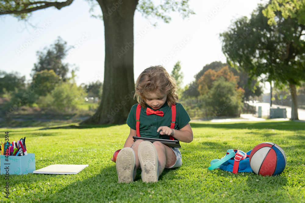 Aufkleber nerd pupil. little child learning outdoor by studying online and working on tablet in green field.