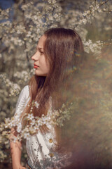 portrait of a beautiful teenage girl who stands near a blossoming tree