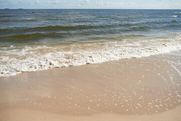 foamy sea water on the beach, golden sand, sunny day