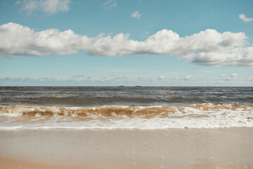 foamy sea water on the beach, golden sand, sunny day
