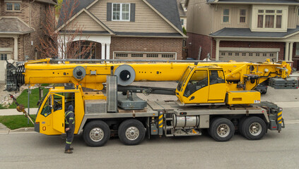 A large truck crane is getting ready for work in a residential area next to the house