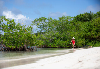 young woman walking on the beach with mangroves in the back
