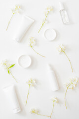 Flat lay composition with cosmetics and jasmine flowers on a light background