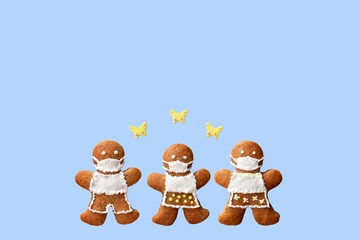 Cute gingerbread family with protective face masks and butterflies, isolated, blue background. Greeting card, copy space for text. Creative concept in coronavirus (COVID-19) time