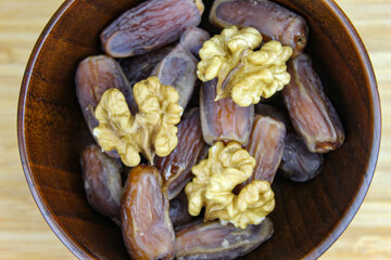Wooden bowl with dates and walnut kernels. Fruit on a wooden tray. Fruit dates. Walnut kernels.
