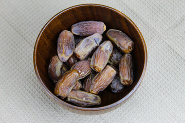 Wooden bowl with dates on the table. Fruit on a wooden tray. Fruit dates. Walnut kernels. The concept of Ramadan.