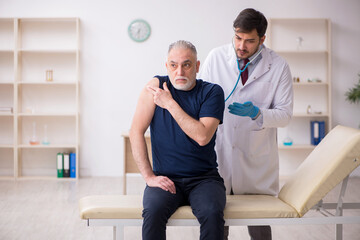 Fototapeta premium Old male patient visiting young male doctor in vaccination conce