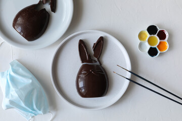 Broken Easter chocolate bunnies and medical mask as symbol of Easter holiday restrictions due to covid-19