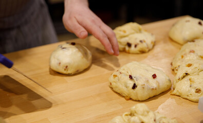 The chef hands divide the sweet dough with raisins into portions on a wooden table. selective focus.High quality photo