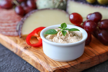 Turkey pate on a meat board made of Italian products and fresh grapes with red pepper and green olives on an olive wood board