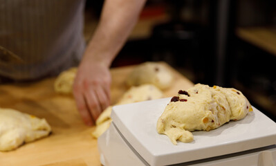 The chef hands divide the sweet dough with raisins into portions on a wooden table. selective focus.High quality photo